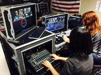 Two people seated at a desk, editing recorded video.